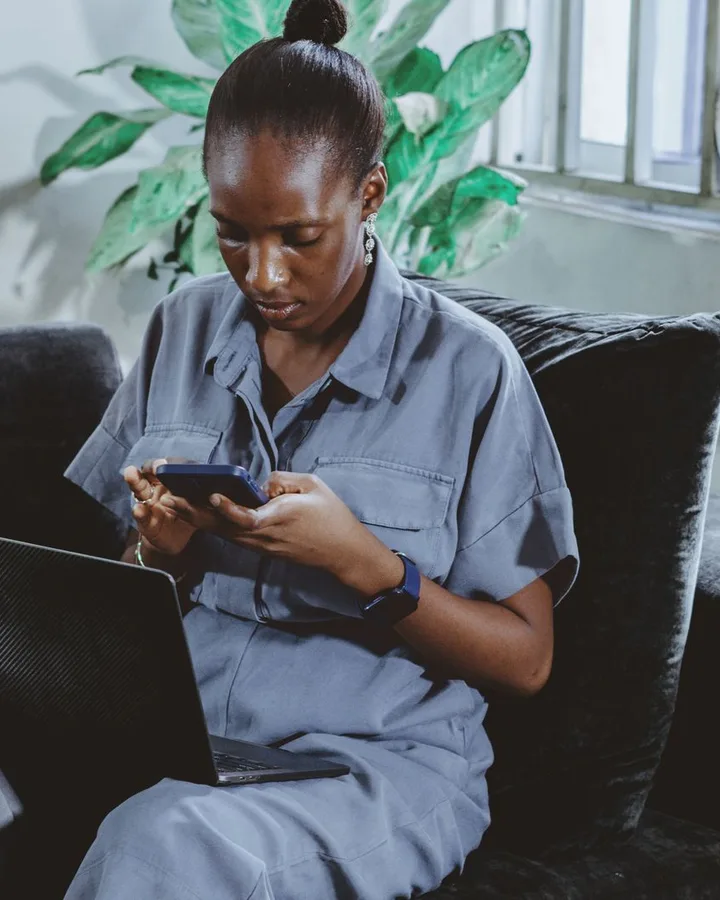 A woman managing orders on her phone and laptop from home