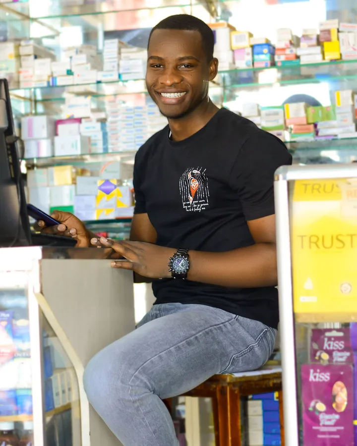 A shopkeeper smiling at the counter of his store, phone in hand